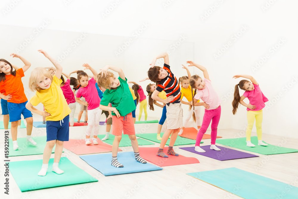 Happy kids doing side bending exercises in gym