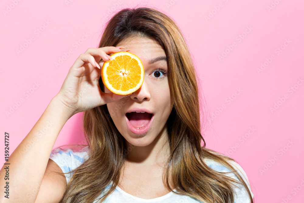 Happy young woman holding orange