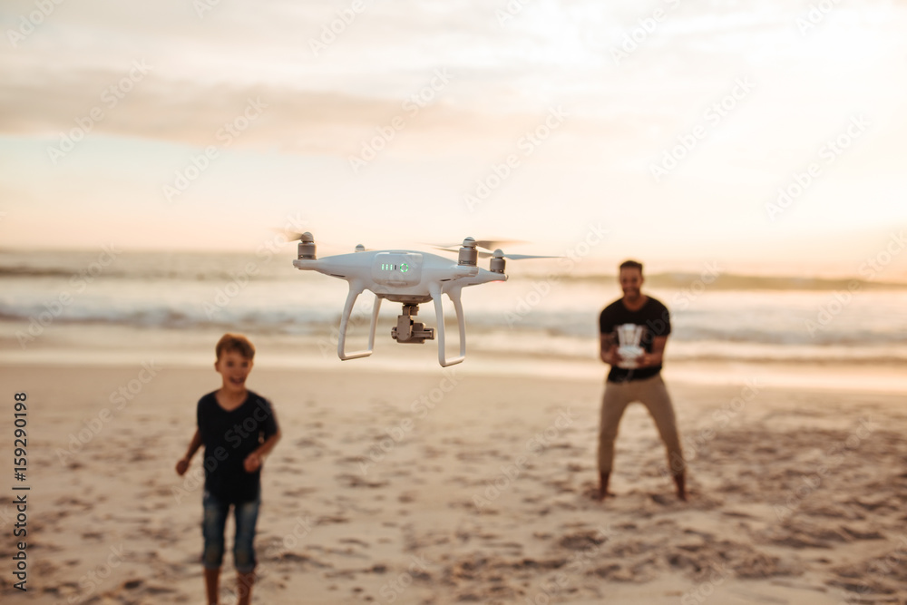 Father and son on summer vacation flying drone on beach