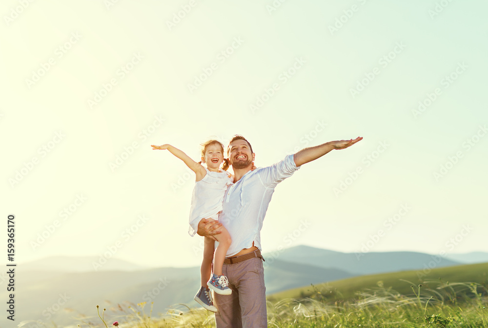 fathers day. child daughter  in the arms of her dad outdoors on a summer