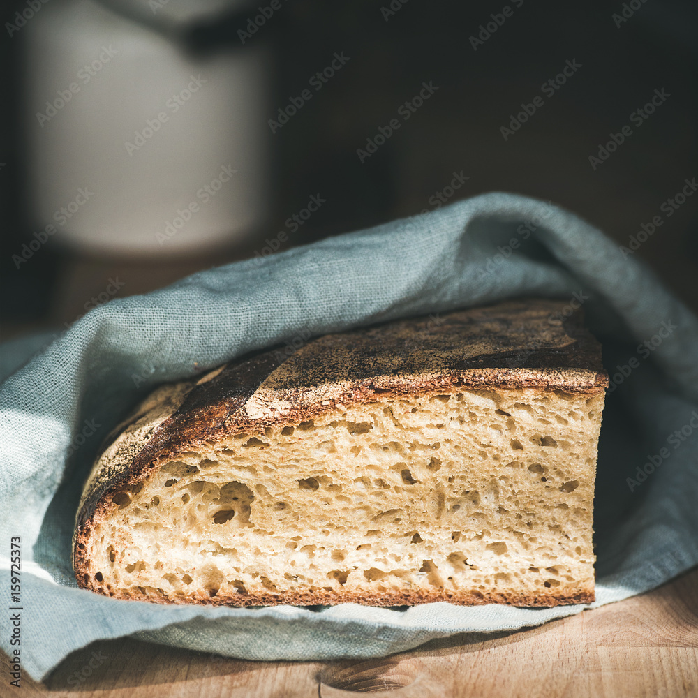 破旧的木板上覆盖着厨房毛巾的质朴的法国黑麦面包，选择性聚焦，s