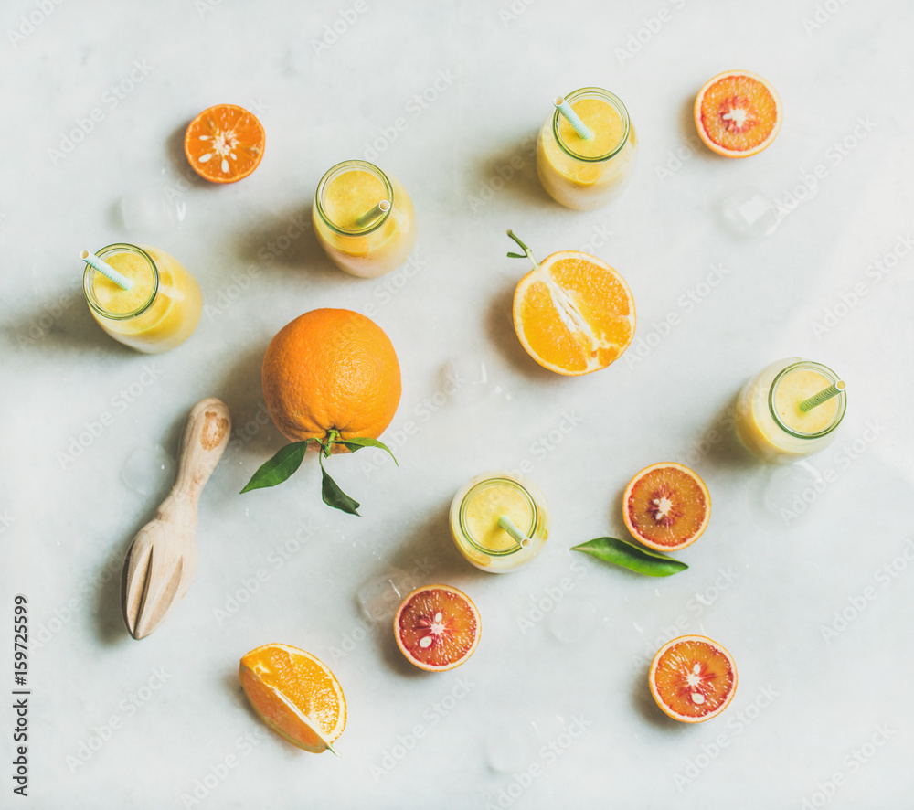 健康的黄色奶昔，配柑橘类水果、生姜和冰块，装在玻璃瓶里，放在浅色大理石桌子b上