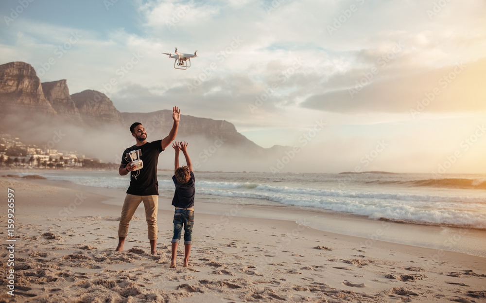 父子俩在海滩上遥控飞行无人机