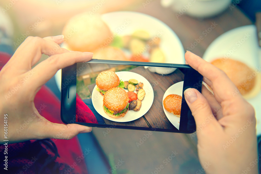 汉堡配蔬菜的美食摄影。社交网络智能手机俯视图