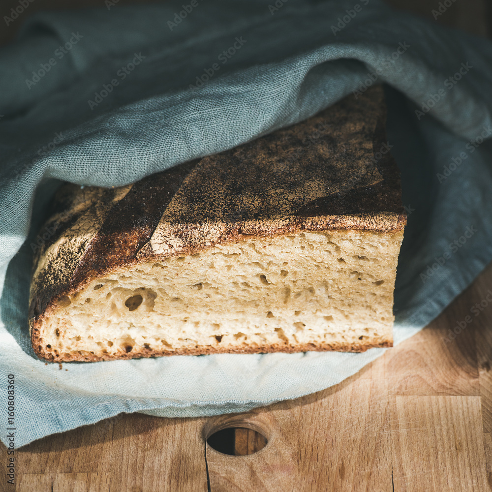 质朴的法国黑麦面包，木板上覆盖着厨房毛巾，选择性聚焦，方形c