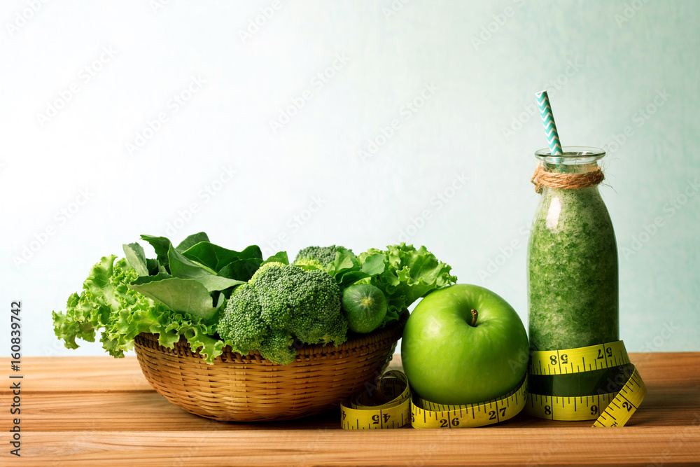 装在木桌上的玻璃瓶里的健康新鲜绿色奶昔汁，配绿苹果和蔬菜