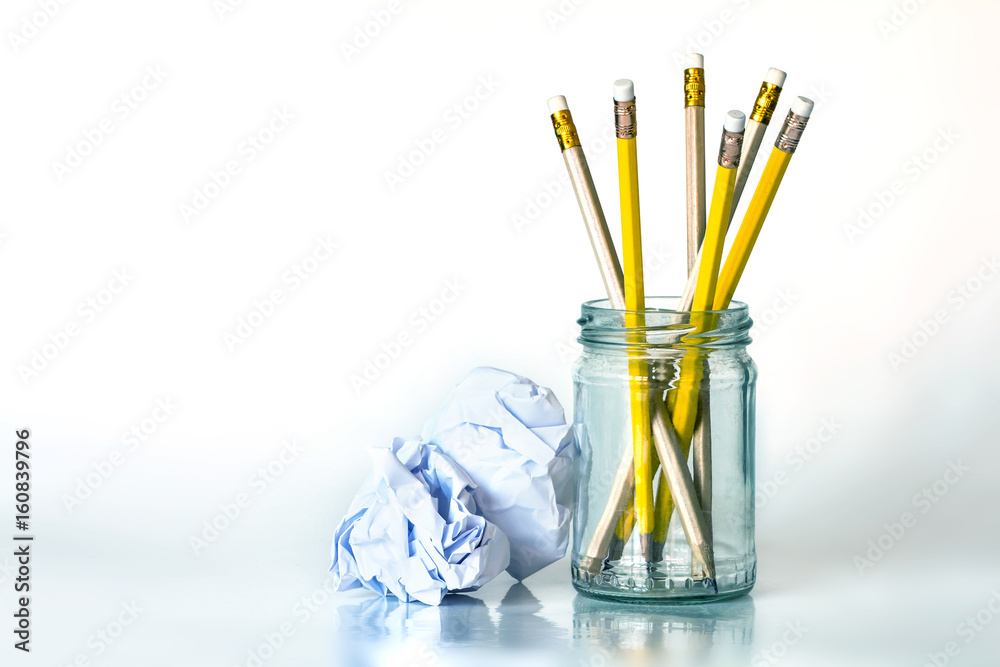 玻璃罐里的金黄色铅笔，白色背景上有皱巴巴的纸，有复制空间，奶油色