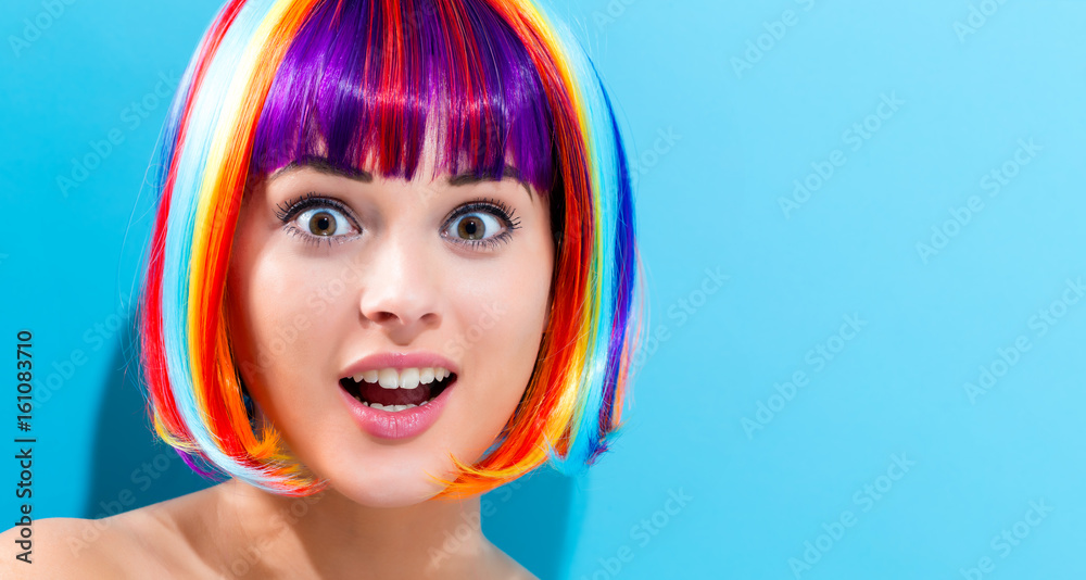 Beautiful woman in a colorful wig on a blue background
