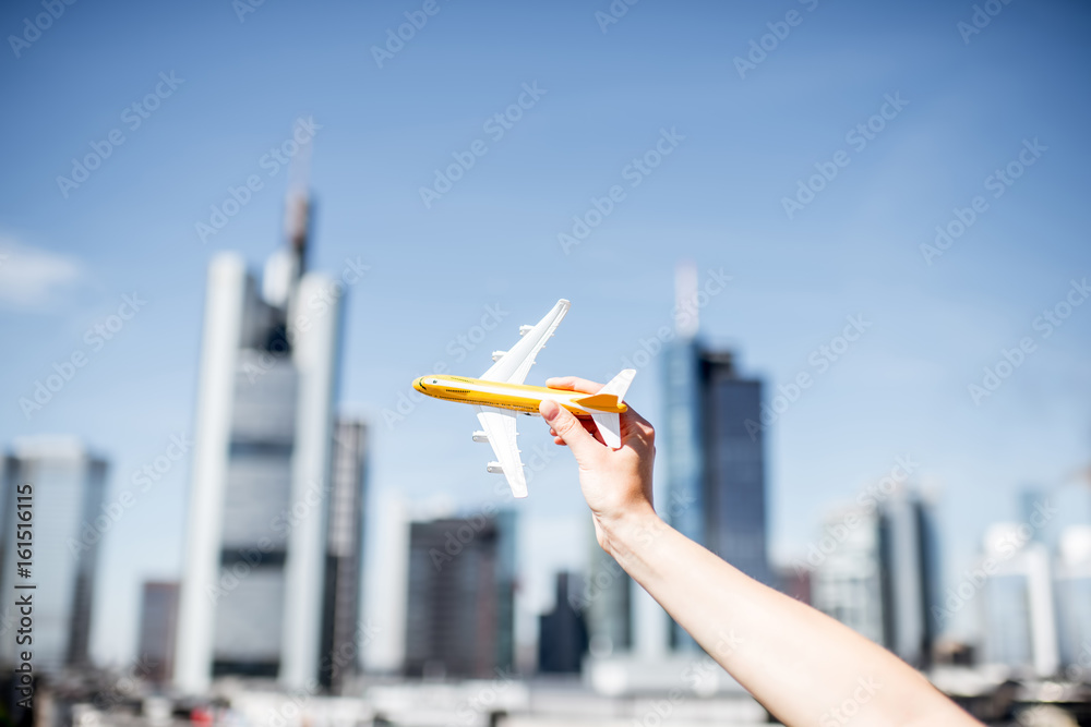在法兰克福的城市景观背景下拿着一架玩具飞机。法兰克福有一个非常大的航空公司连接