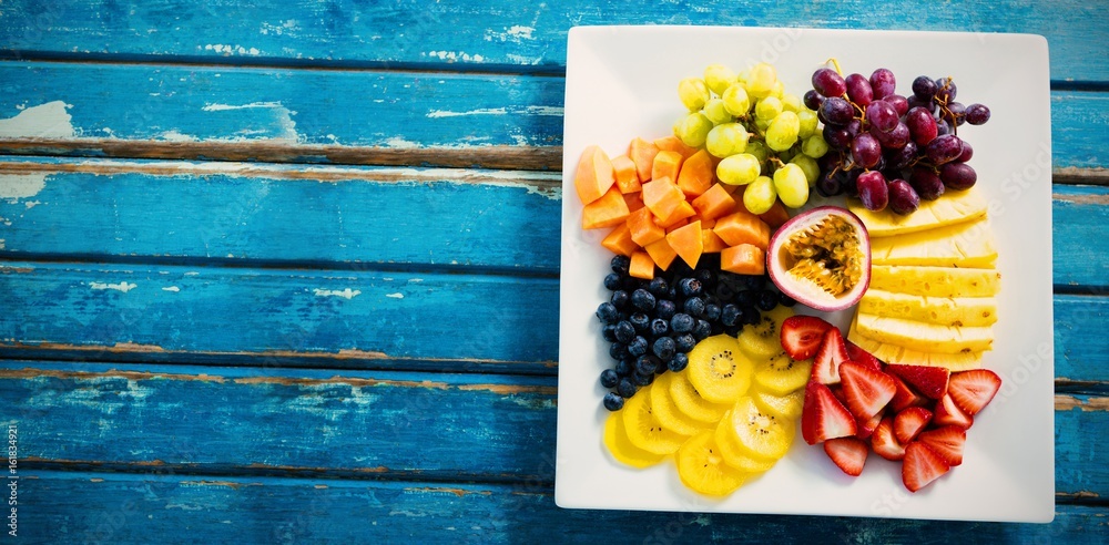 Fresh fruits in white plate on blue table