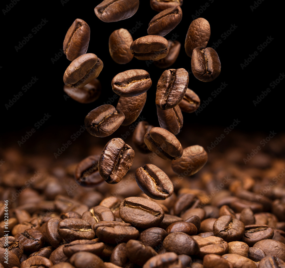 Falling coffee beans on dark background, close-up