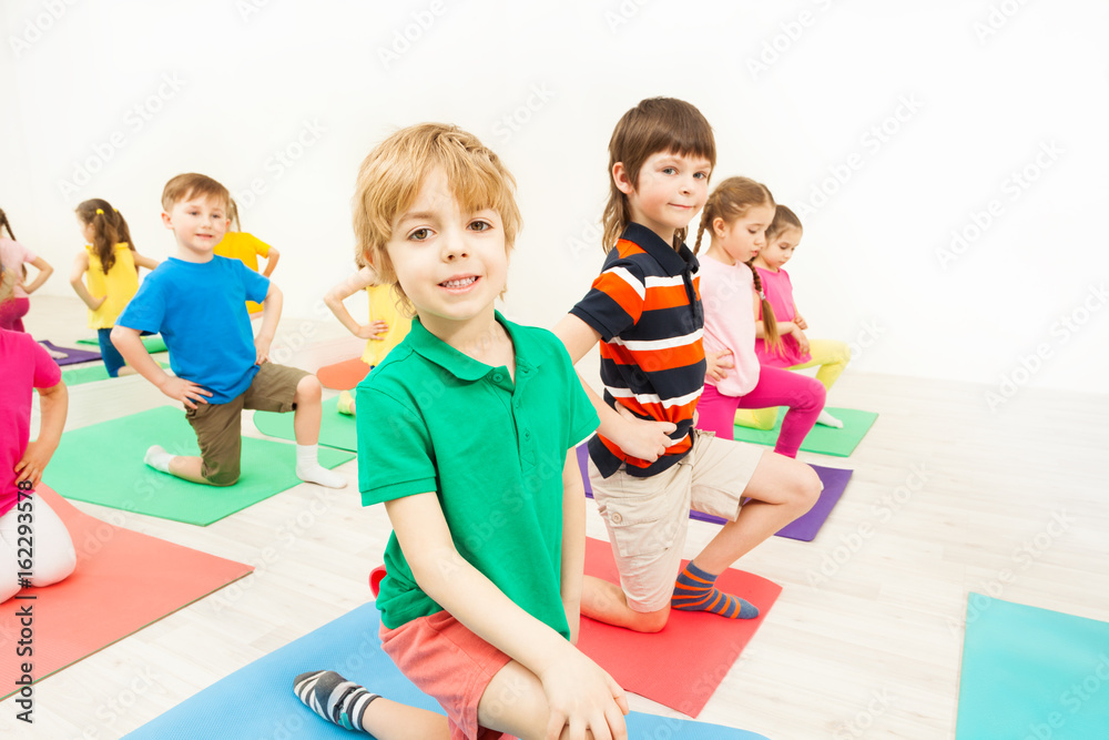 快乐的孩子们在健身房的垫子上练习体操