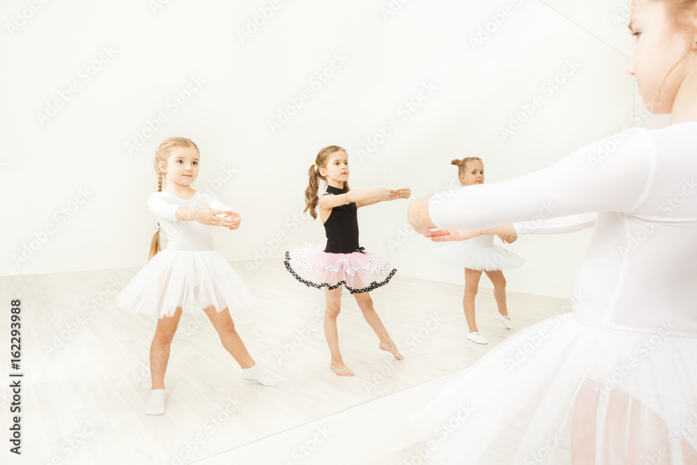 女孩在芭蕾舞工作室的镜子附近练习