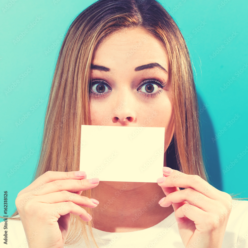 一个女人在脸前拿着一张空白的信息卡
