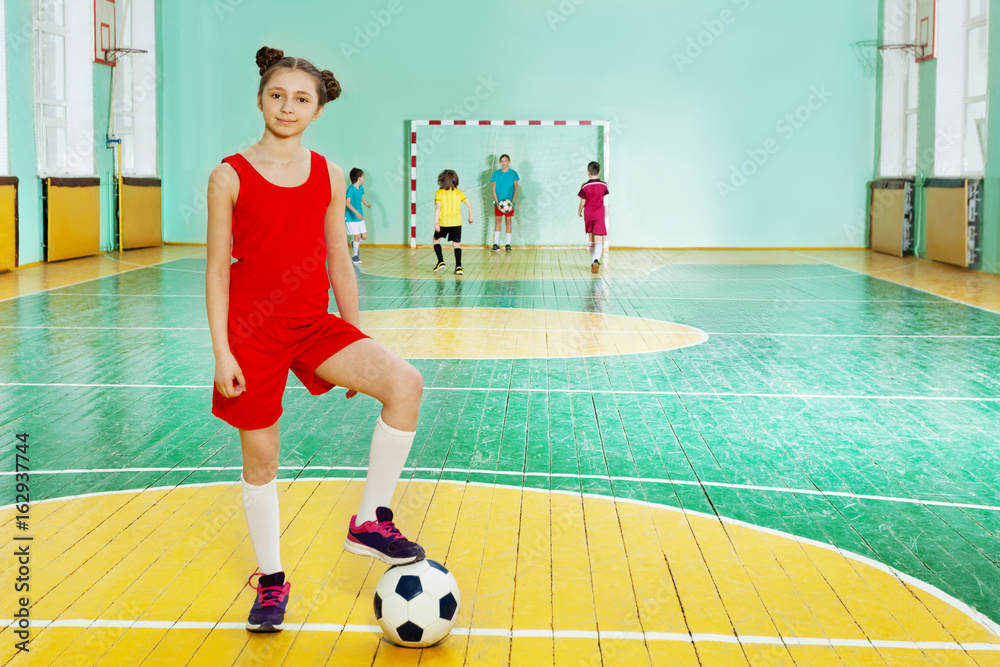 运动女孩拿着足球站在五人制足球赛中