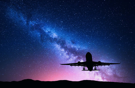 银河系和飞机的轮廓。客机在星空中飞行的风景
