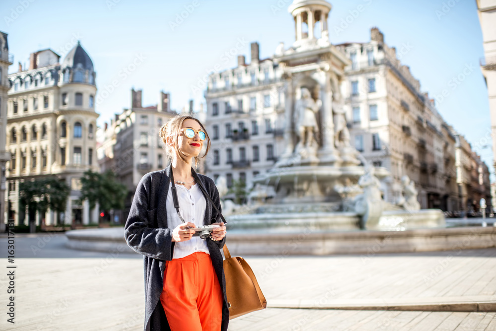 年轻女子拿着相机站在雅各宾派广场上，背景是著名的喷泉