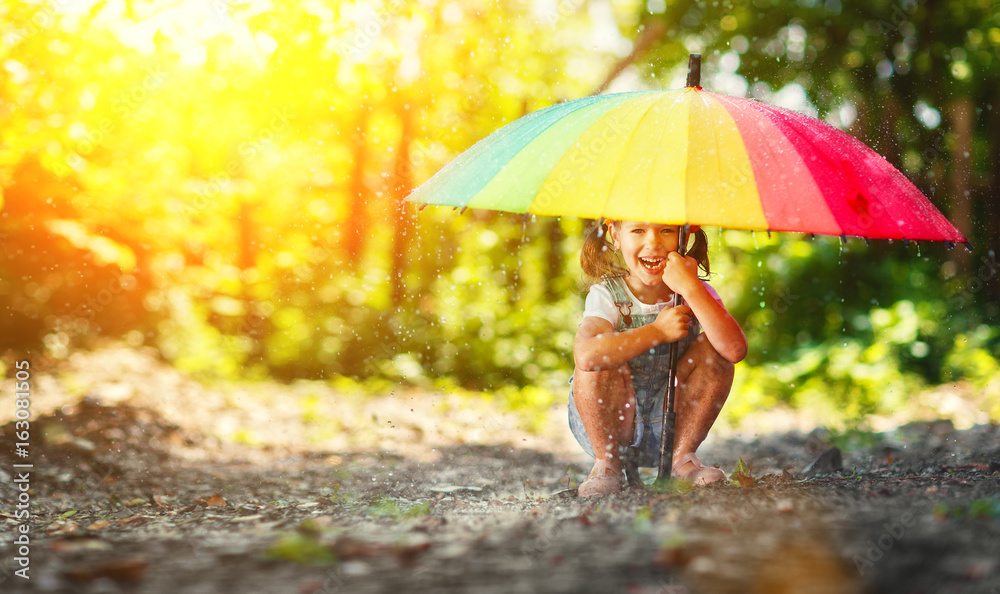 快乐的小女孩撑着伞在夏雨下嬉笑玩耍