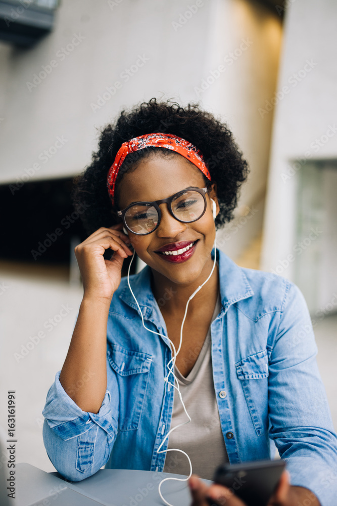 微笑的年轻非洲女企业家在听音乐