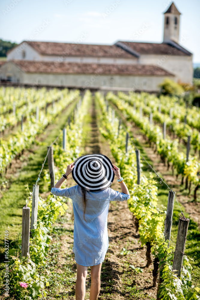 Young woman in striped hat enjoying beautiful sunset view on the vineyard in Bordeaux region in Fran