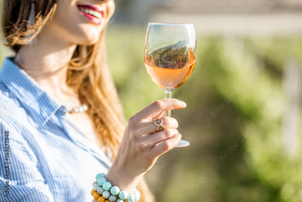 F日落时，一位年轻女子站在波尔多地区葡萄园的户外品尝葡萄酒