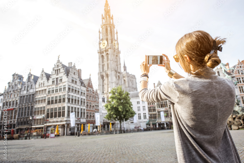 年轻女性游客用手机拍摄矗立在大市场广场上的著名大教堂