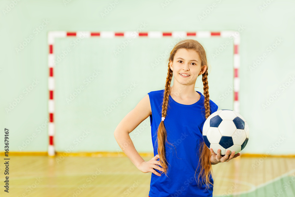 青少年女孩在学校体育馆拿着足球