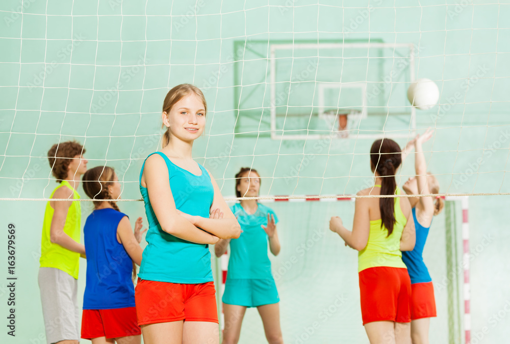 微笑的少女站在排球网旁边