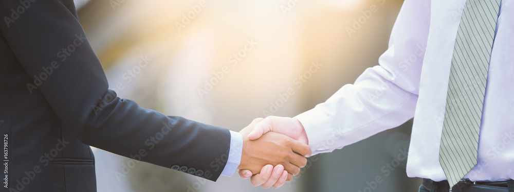 Business handshake concept. shaking hand of two businessman negotiation closing a deal city backgrou