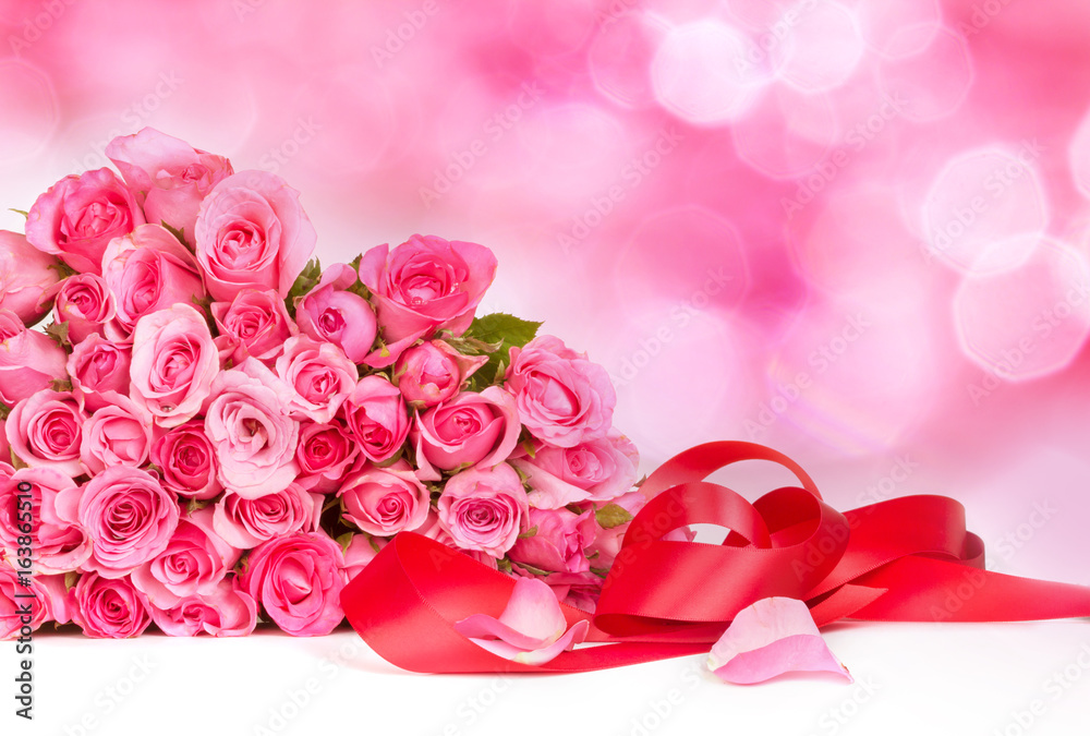在甜美的粉红色背景上绽放甜美的粉红色玫瑰花瓣，浪漫和爱情卡片概念