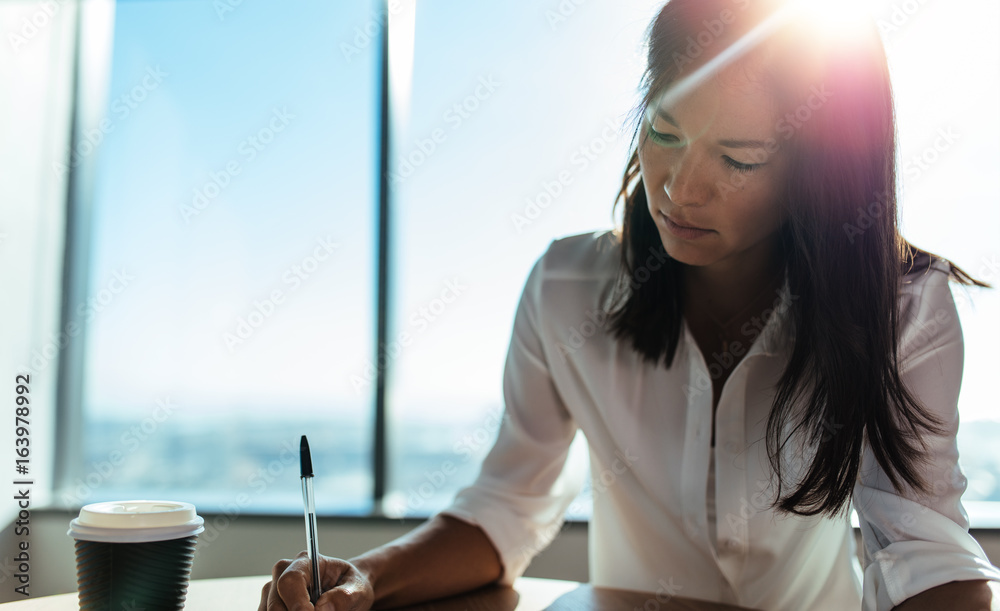 Closeup of a businesswoman sitting at coffee table doing office