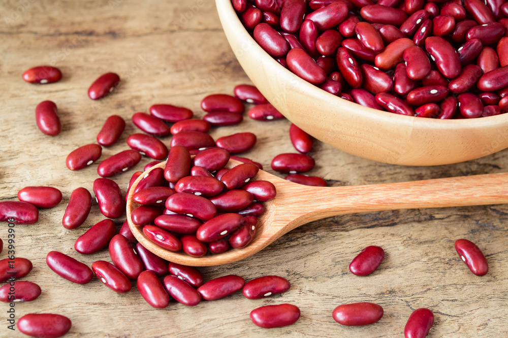 Red Kidney Bean in wooden spoon and wooden bowl on wooden background, Top view.