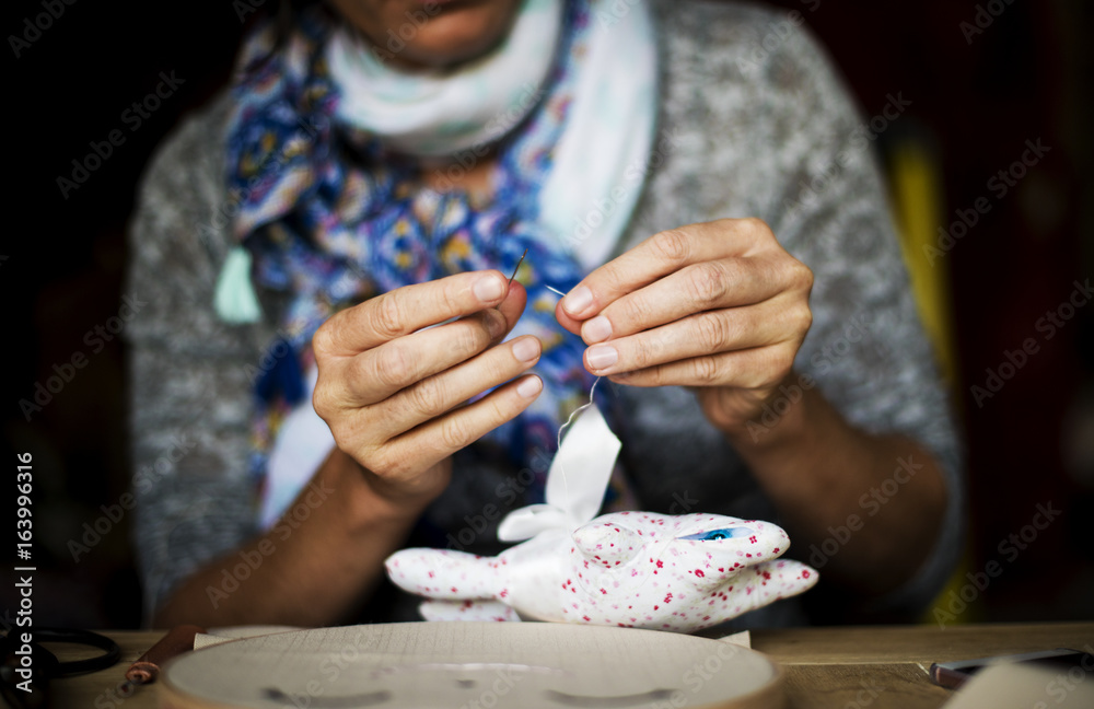 女人在桌子上缝制手工娃娃