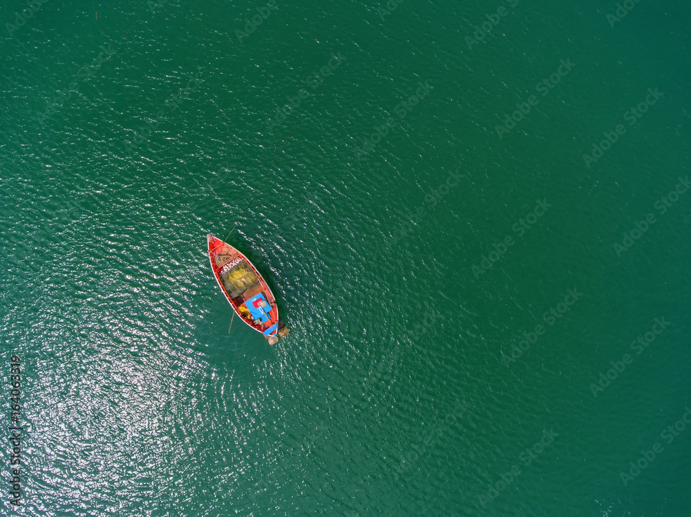 Fishing boat floating in the sea. The beautiful bright blue water in a clear day.Aerial view.Top vie