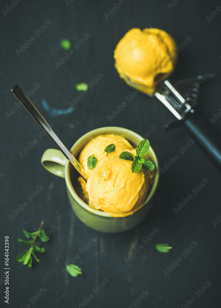 清爽的夏季甜点。芒果冰糕冰淇淋勺，绿色杯子里放着新鲜薄荷，配上黑色的woo