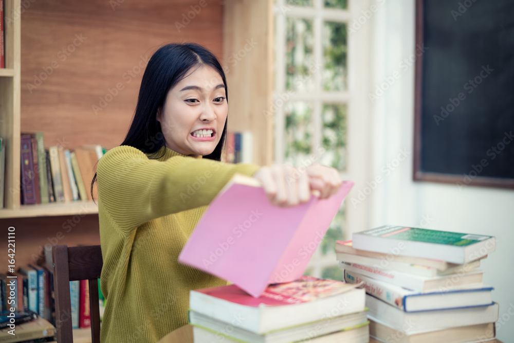 亚洲女大学生愤怒地撕毁了她的书，因为她读的书不理解