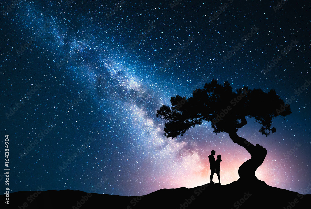 山上树下的银河与拥抱的情侣。夜晚的星空和思猴景观