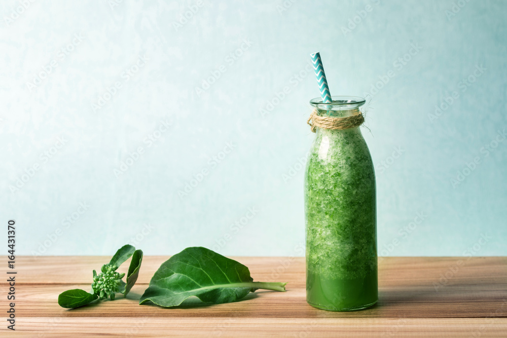 Healthy fresh  green smoothie juice in the glass bottle on wooden table for healthy detox and diet  
