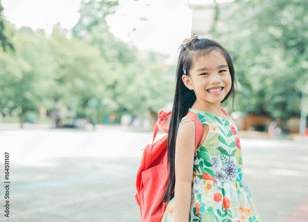 快乐的亚洲女孩背着背包从家里来到学校