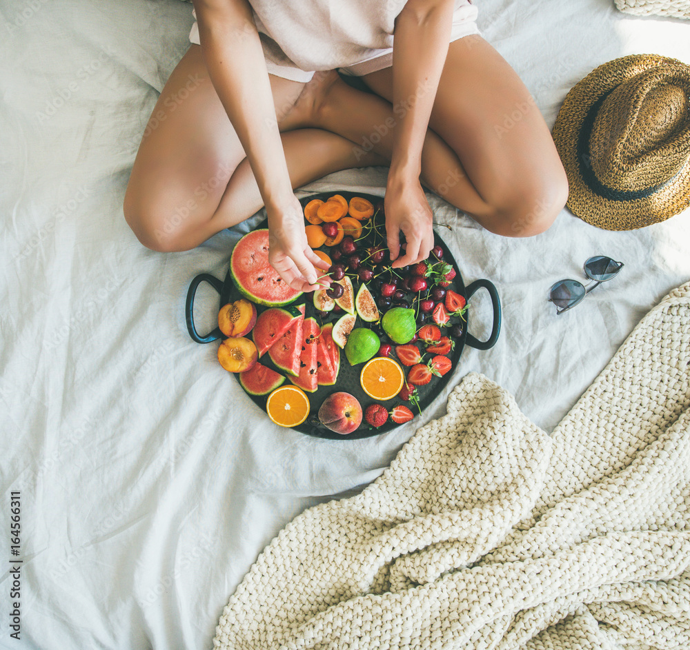 夏季健康生素食主义者在床上吃早餐的概念。年轻女孩穿着浅色ho