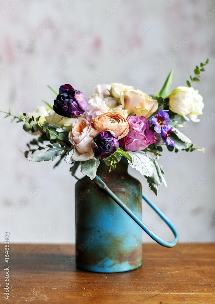 木桌上金属花瓶里摆放的各种鲜花