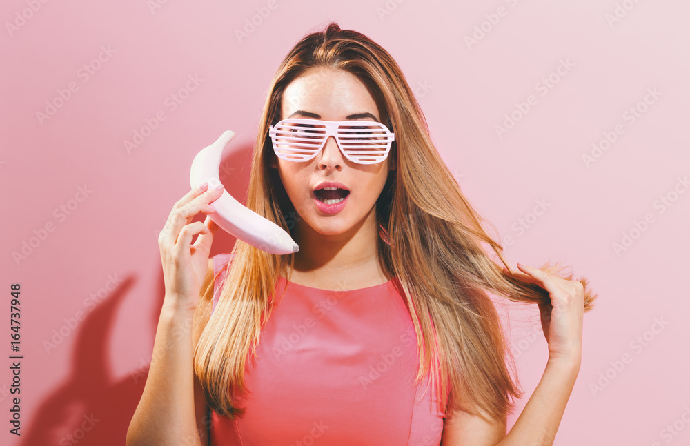 年轻的粉红色女人，带着时髦的香蕉和遮光帘