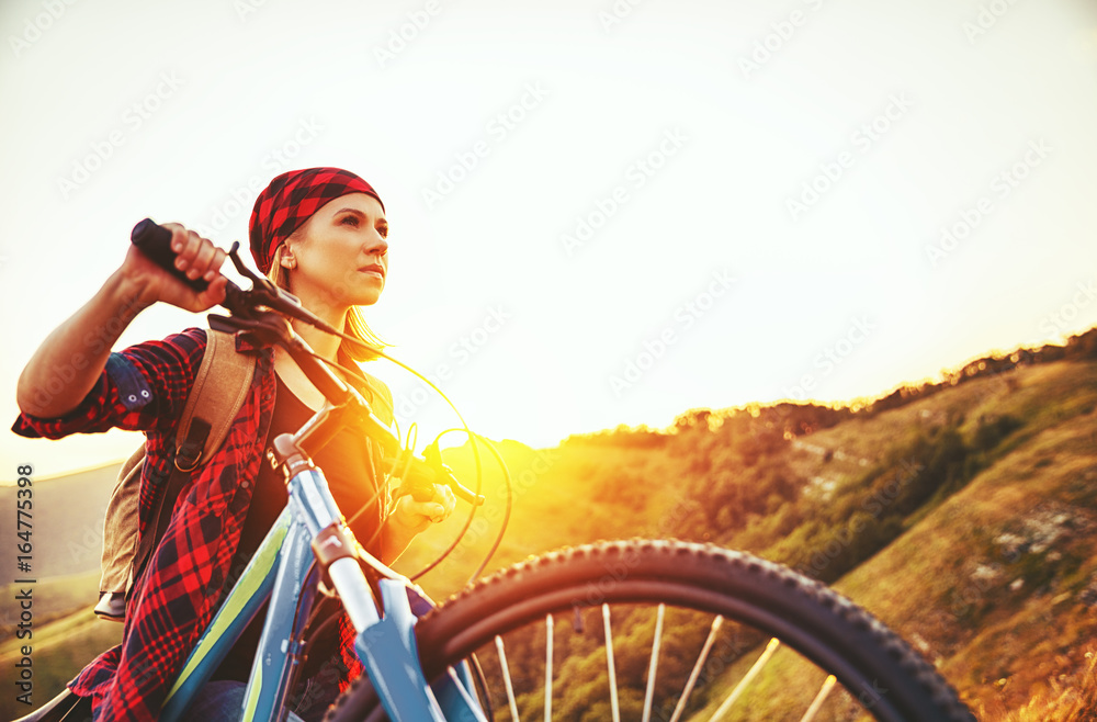 夏季户外徒步旅行日落时骑自行车在山顶的女游客