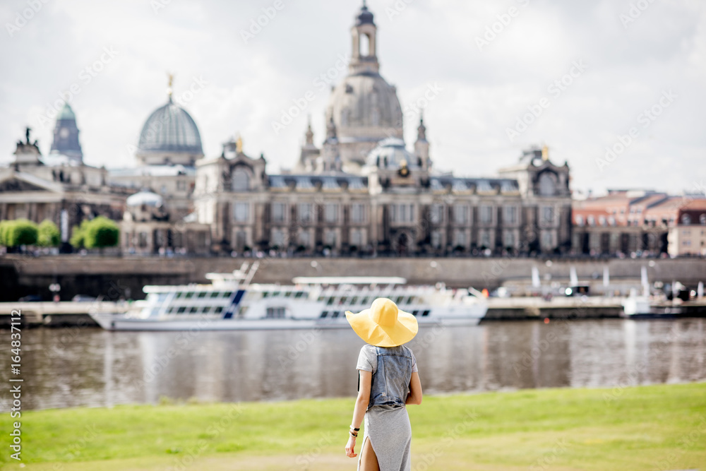 戴着黄色帽子的年轻女游客站在后面，欣赏德累斯顿老城的美景。
