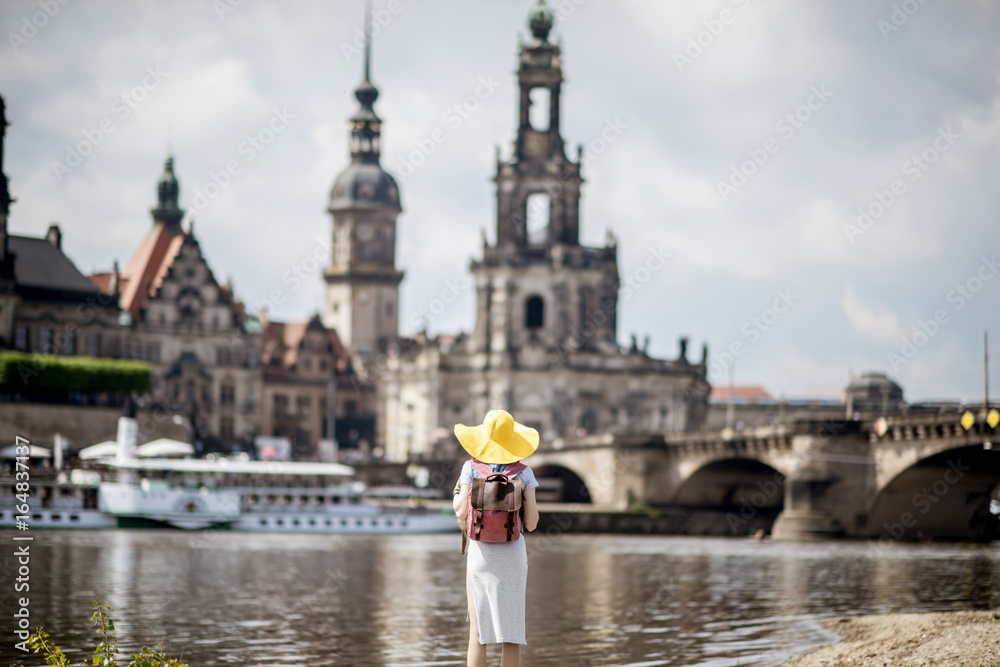 戴着黄色帽子的年轻女游客站在后面，欣赏德累斯顿老城的美景。