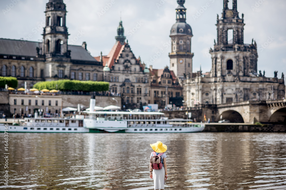 Young woman tourist in yellow hat standing back and enjoying great view on the old town of Dresden, 