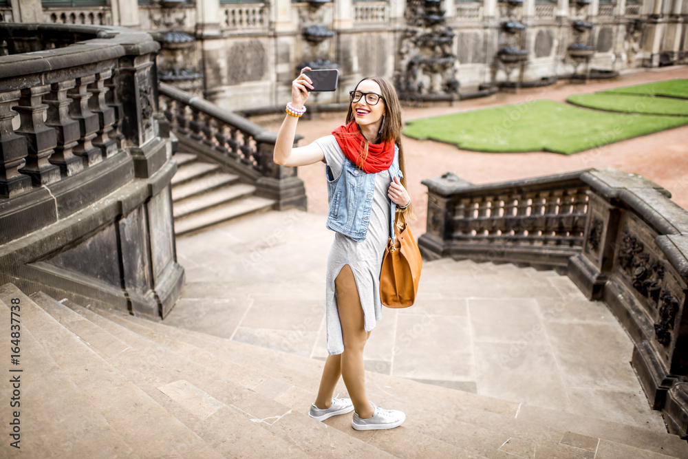 年轻女性游客在参观德国德累斯顿市的旧宫殿时用手机拍照