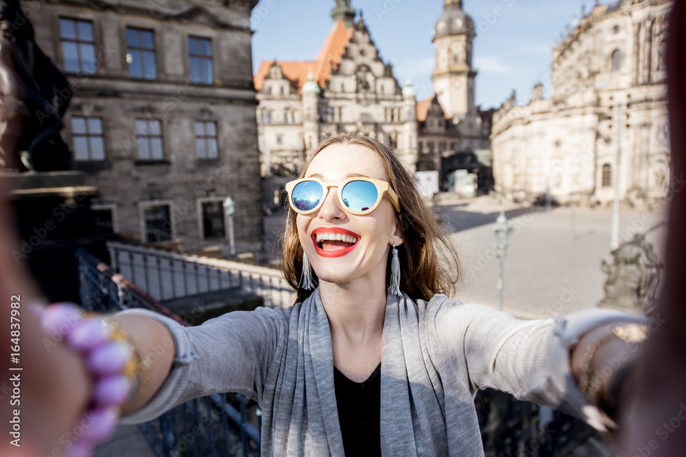Young woman tourist making selfie photo on the old town background in Dresden, Germany