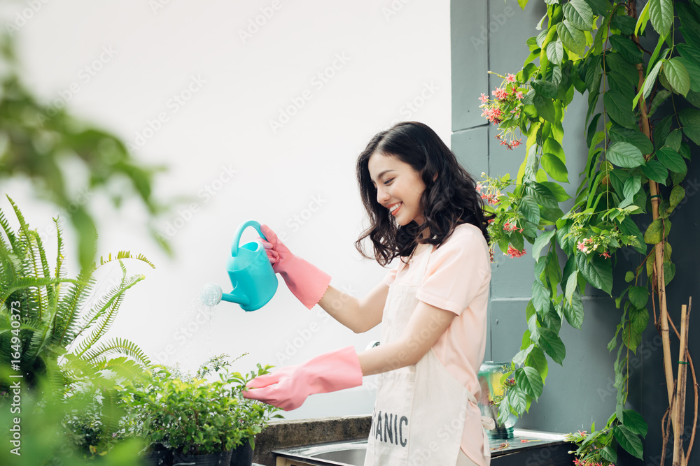 亚洲女园丁在夏天给花园里的花浇水