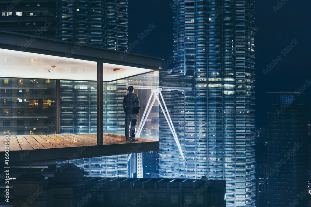 商人在一间现代化的空中办公室里，晚上可以看到美丽的城市天际线。